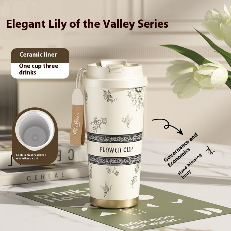 Ceramic travel mug with floral design on a table with tulips in the background