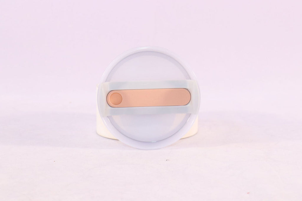 Clear container with a gold-colored object on a light purple background