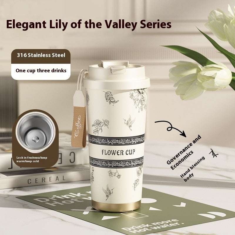 Floral-patterned tumbler with text on a table with flowers in the background