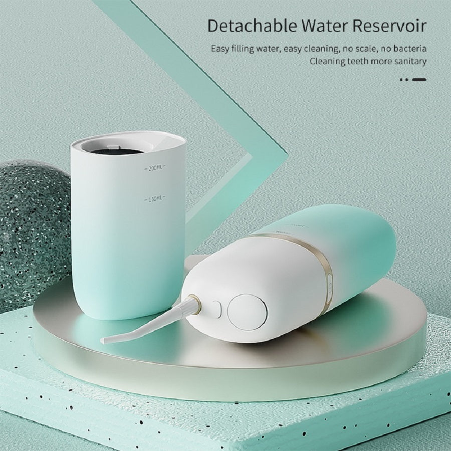 Mint green and white dental cleaning device with detachable water reservoir on a light green background.