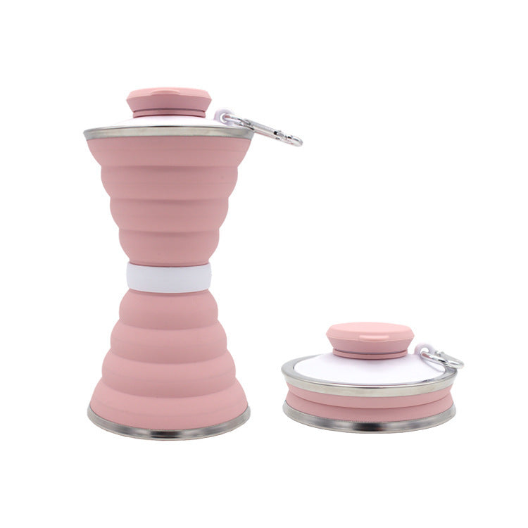 Pink collapsible water bottle with carrying strap on a white background