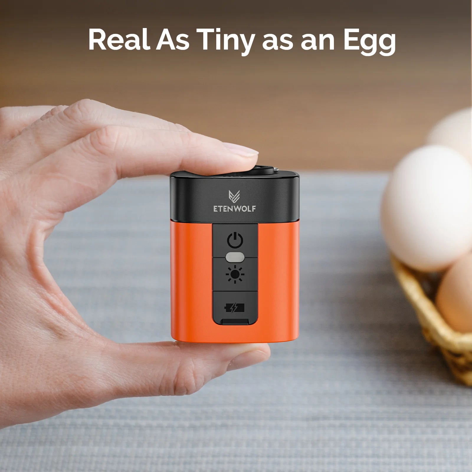 Small orange and black device held in a hand with eggs in the background, featuring the brand 'Etenwolf'.