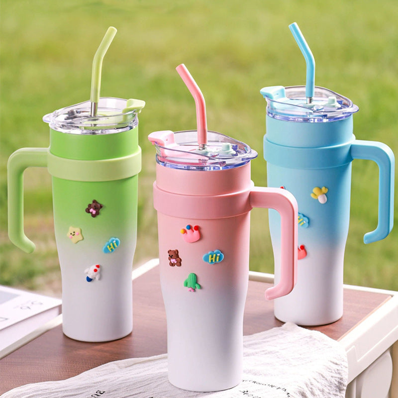 Three colorful tumblers with straws on a wooden surface with a grassy background