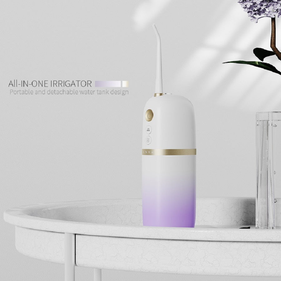 White and purple dental irrigator on a bathroom counter with text 'All-in-One Irrigator' and 'Portable and detachable water tank design'.