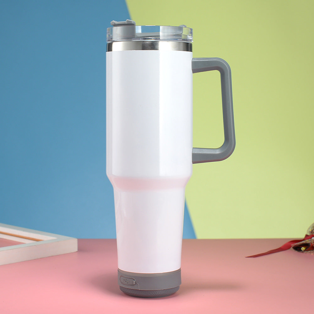 White insulated mug with gray handle and base on a pink surface with a colorful background
