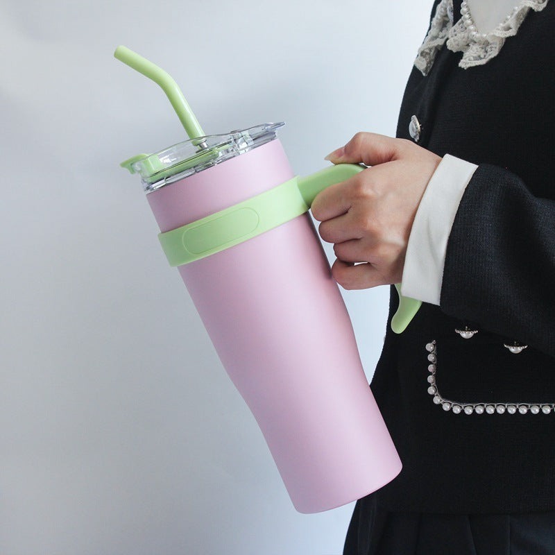 Person holding a pink tumbler with a green straw and band against a light gray background