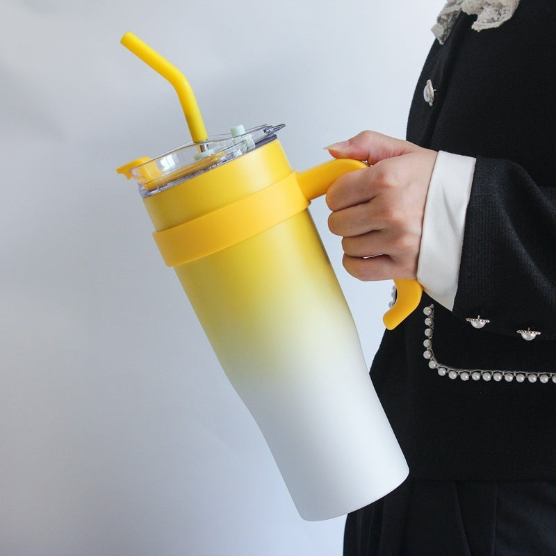 Person holding a yellow and white gradient tumbler with a straw on a plain background